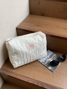Detail of white textured nylon cosmetic bag with patch zipper and lifestyle props