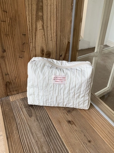Detail of white pleated nylon storage bag with logo on a wooden bench setting
