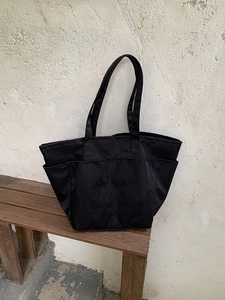 Dettaglio della borsa tote in nylon nero capiente con molteplici tasche funzionali
