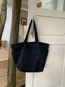 Dettaglio di una grande borsa tote in nylon nero appesa per il pendolarismo quotidiano
