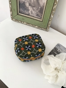 Floral embroidery dark green mini makeup pouch with vintage patterns on a white desk