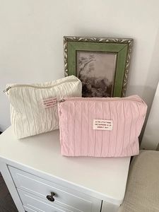 Macro detail of white and pink pleated nylon cosmetic bags with woven labels and zippers