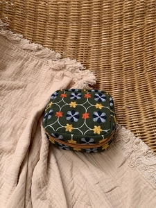 Close-up of floral embroidery on dark green canvas cosmetic bag with detailed stitching