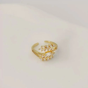 Elegant gold leaf open ring with shimmering zircon crystals on a minimalist background