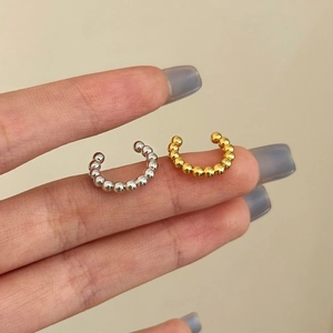 Minimalist beaded ear cuffs in gold and silver finish shown on a fingertip