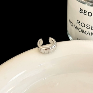 Detailed view of silver ear cuff with vertical grooves on a ceramic edge