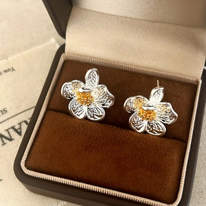 Macro shot of silver floral earrings with gold center in a velvet gift box