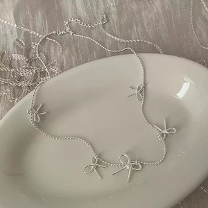 French style silver necklace with five textured bow pendants on a delicate bead chain