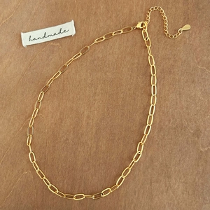 Detail of golden paperclip chain necklace with lobster clasp and teardrop charm