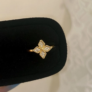 Macro view of a gold flower ring with zircon inlays on a black velvet box