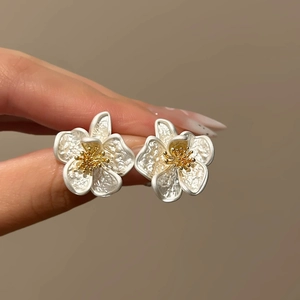 Elegant matte white flower stud earrings with textured petals and golden stamen detail