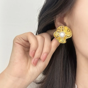 French vintage gold flower earrings with white pearl center worn by a model