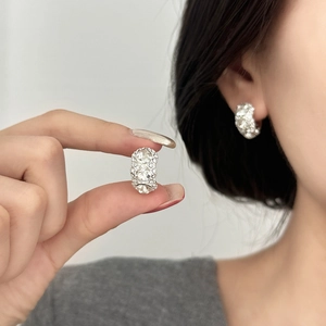 Detail view of silver luxury earrings with three large vertical zircons and pavé crystals