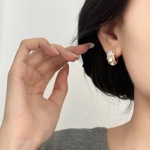 Detailed view of luxury C-shaped gold earrings with large brilliant-cut sparkling crystals