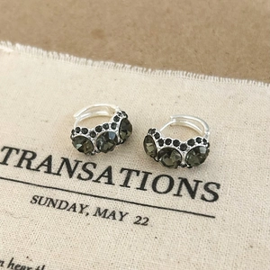 Close-up of silver hoop earrings with dark grey pave-set crystals on canvas texture