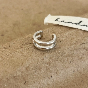 Macro shot of minimalist silver double-layered ear cuff on a brown craft paper backdrop