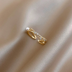 Elegant gold pearl and zircon crisscross open ring on champagne silk fabric background