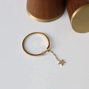 Détail d'une bague à pendentif étoile dorée avec zircon et chaîne fine élégante