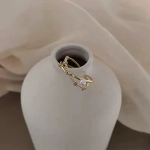Detail of gold double-layer cross ring with white pearl and sparkling zircon accents