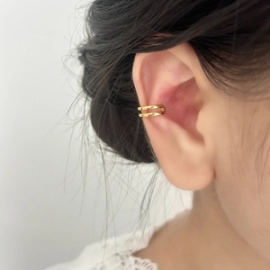 Close-up of minimalist double-line gold ear cuff worn on the ear cartilage without piercing