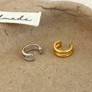 Set of gold and silver double-layered C-shaped ear cuffs on a textured tray