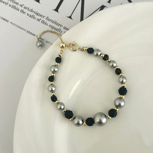 Détail du bracelet réglable avec perles grises et noires sur plateau en céramique