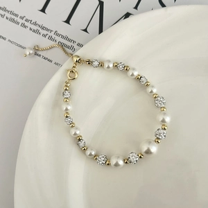 Détail d'un bracelet en perles ajustable avec boules Shamballa scintillantes et or