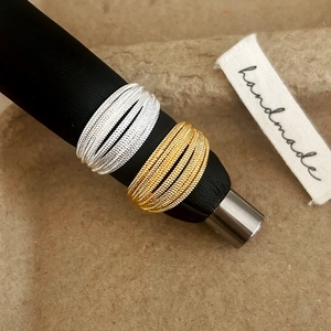 Minimalist geometric multi-layer woven ring in gold and silver finish on display