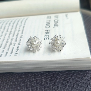 Vintage floral pearl earrings with zircon petals on an open book background