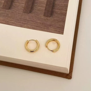 Close-up of minimalist 18K gold-plated geometric hoop earrings on a neutral background