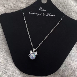 Elegant silver bow necklace with iridescent pearl pendant on a black display card