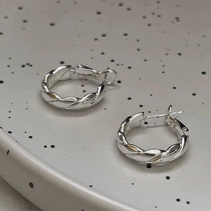 Créoles torsadées argentées avec finition brillante présentées sur un plateau chic