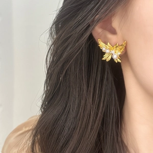 Elegant gold butterfly earrings with white pearls and sparkling crystals on model