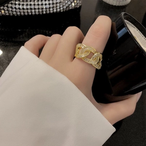 Fashion gold-plated link ring with white zircon stones on a black background