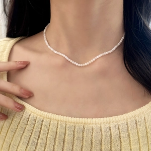 Elegant French minimalist necklace featuring tiny white shell pearls on a model