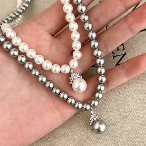 Elegant pearl necklace with crown pendant featuring white and grey beads in high luster