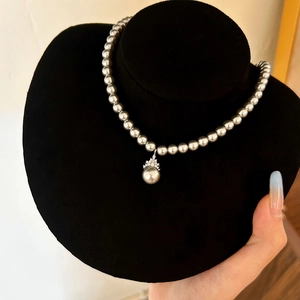 Detail of silver grey pearl necklace with crystal pavé pendant on black velvet stand