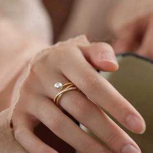 Elegant gold pearl cross ring with cubic zirconia worn by model in soft natural light