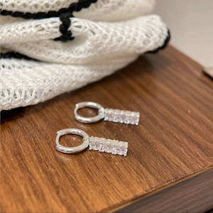 Elegant silver hoop earrings with shimmering zircon rectangle charms on a wooden surface