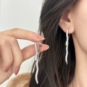 Silver snake earrings with white zircons and green gem eyes on a model for a luxury look