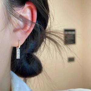 Silver hoop earrings with vertical triple zircon crystals worn by a female model