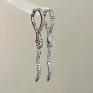 Detail of silver snake drop earrings with pave white zircon and green crystal eyes