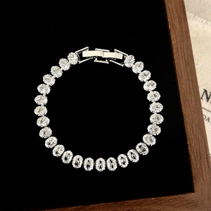 Top view of shiny silver tennis bracelet with oval cubic zirconia on black velvet tray