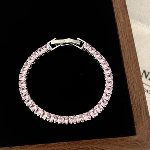 Close-up of pink square-cut zircon tennis bracelet in silver-tone setting on black velvet