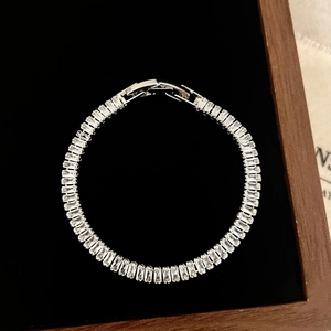 Macro view of silver bracelet featuring baguette-cut zircon stones and a classic fold-over clasp