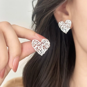 Elegant hollow heart earrings with lace texture for women shown in model ear piercing