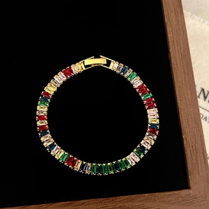Detailed macro view of rainbow baguette-cut gemstone tennis bracelet on black velvet