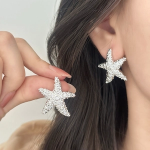 Boucles d'oreilles étoile de mer argentées avec cristaux portées pour un look de vacances