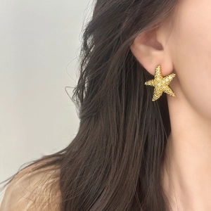 Élégantes boucles d'oreilles étoile de mer dorées avec strass portées par un mannequin