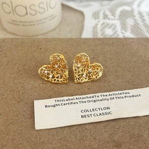 Detailed view of hollow heart-shaped gold stud earrings set with sparkling zircons